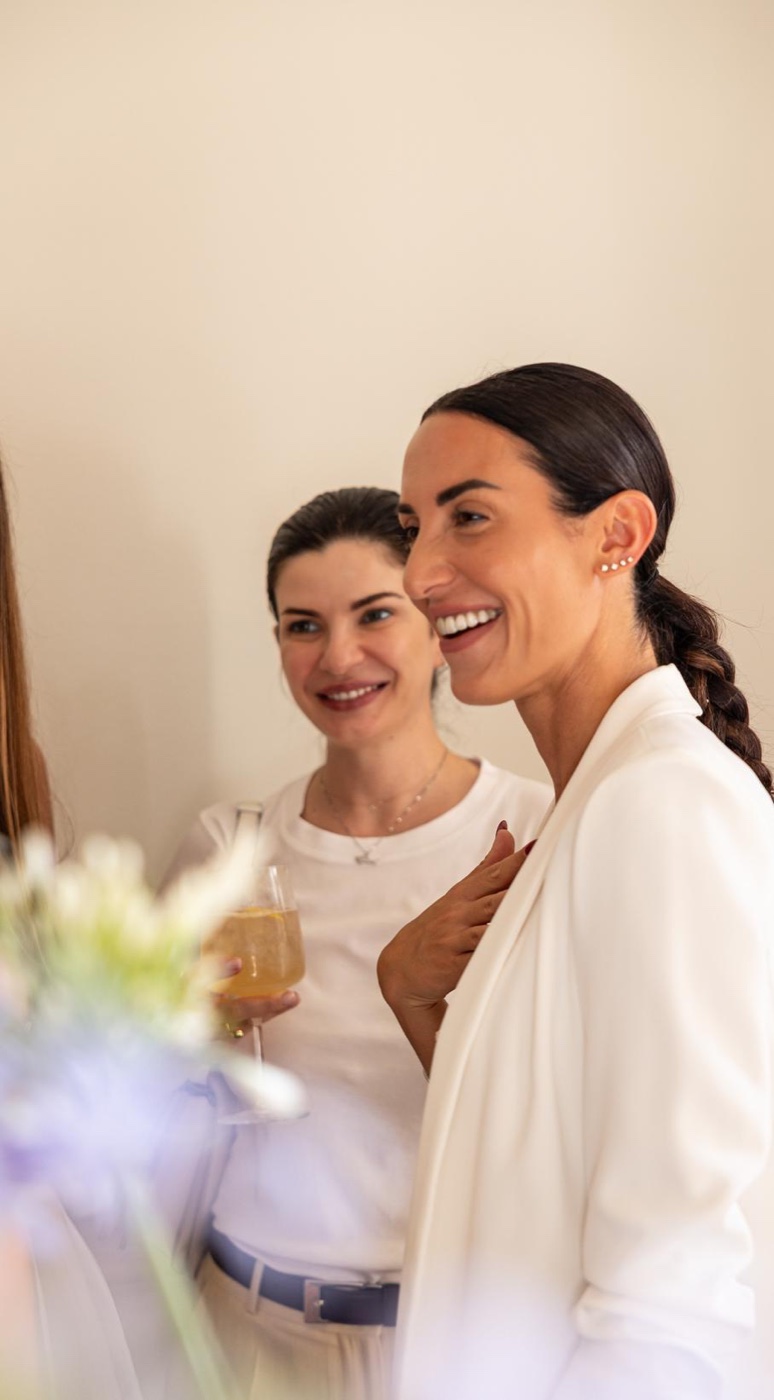 Two guests in ivory clothing sharing a smile and a conversation, with flowers in the foreground at Salotto Duomo